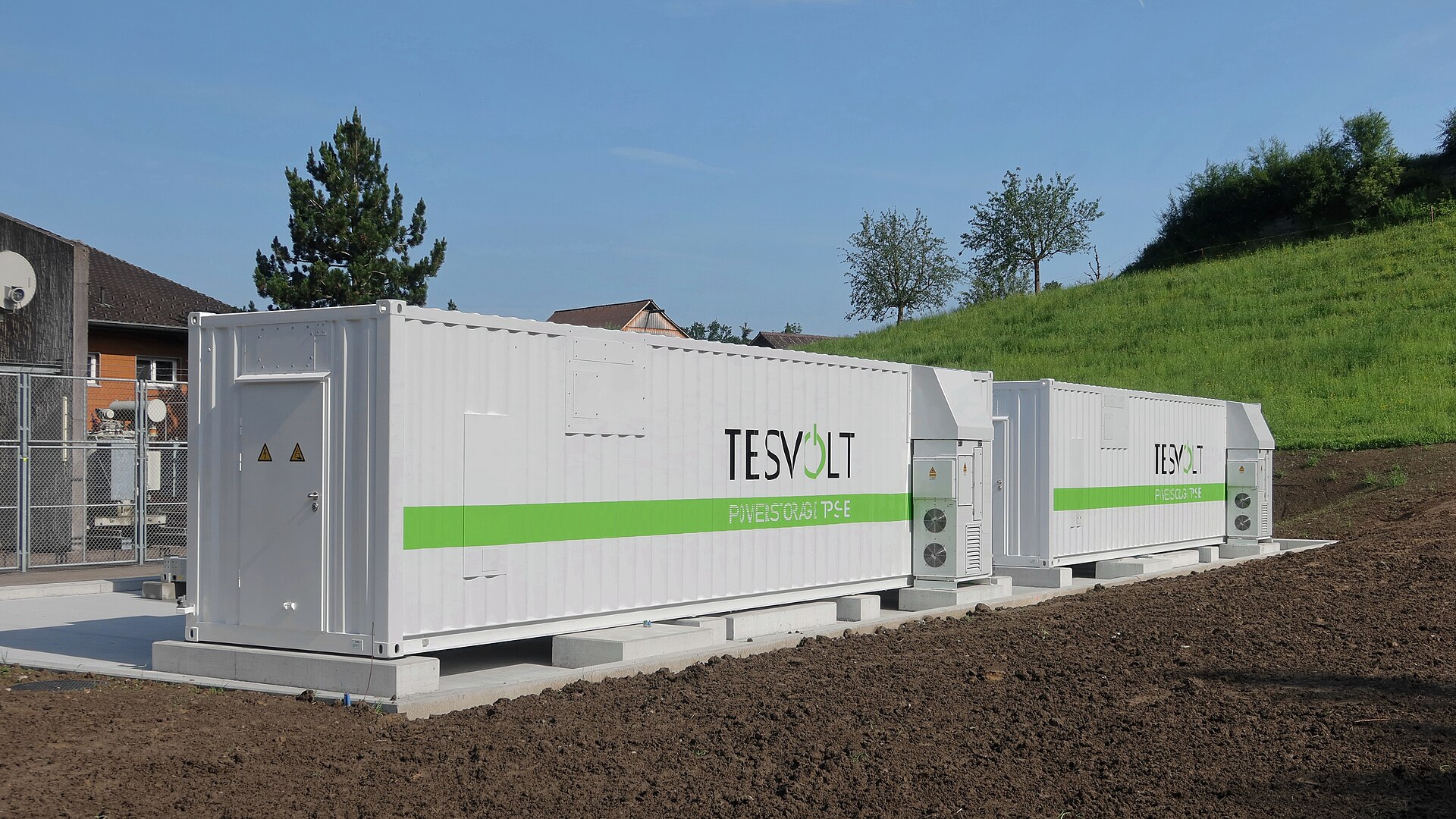 Dois contêineres industriais de armazenamento de energia em baterias instalados sobre base de concreto